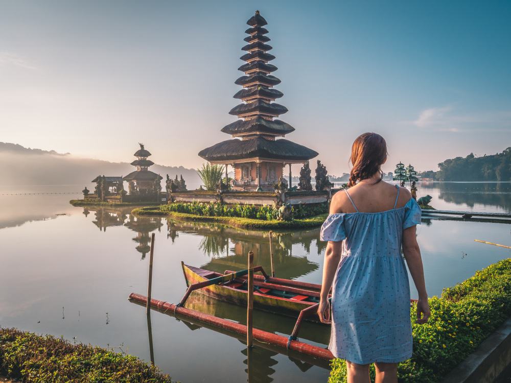 Mujer joven cerca del templo de Pura Ulun Danu Bratan cerca del lago Beratan en la isla de Bali, en el este de Indonesia.  Imagen emblemática de Bali y el sudeste asiático.  Fondo de pantalla de viajes y aventuras.