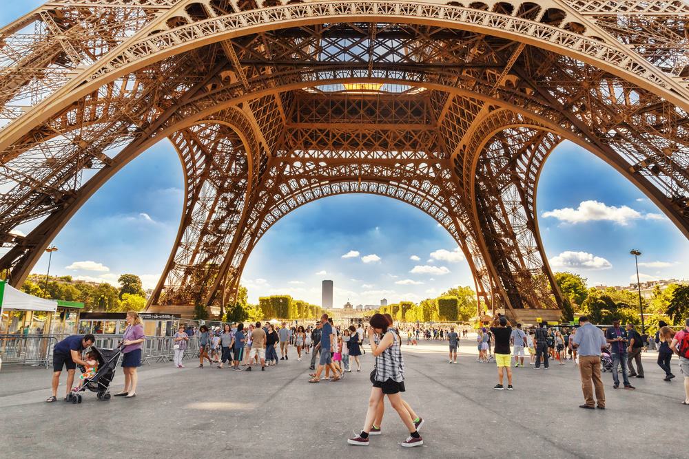 Turistas paseando bajo la Torre Eiffel